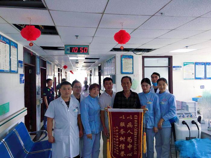 患者家属手握感谢锦旗与医护人员合影.jpg